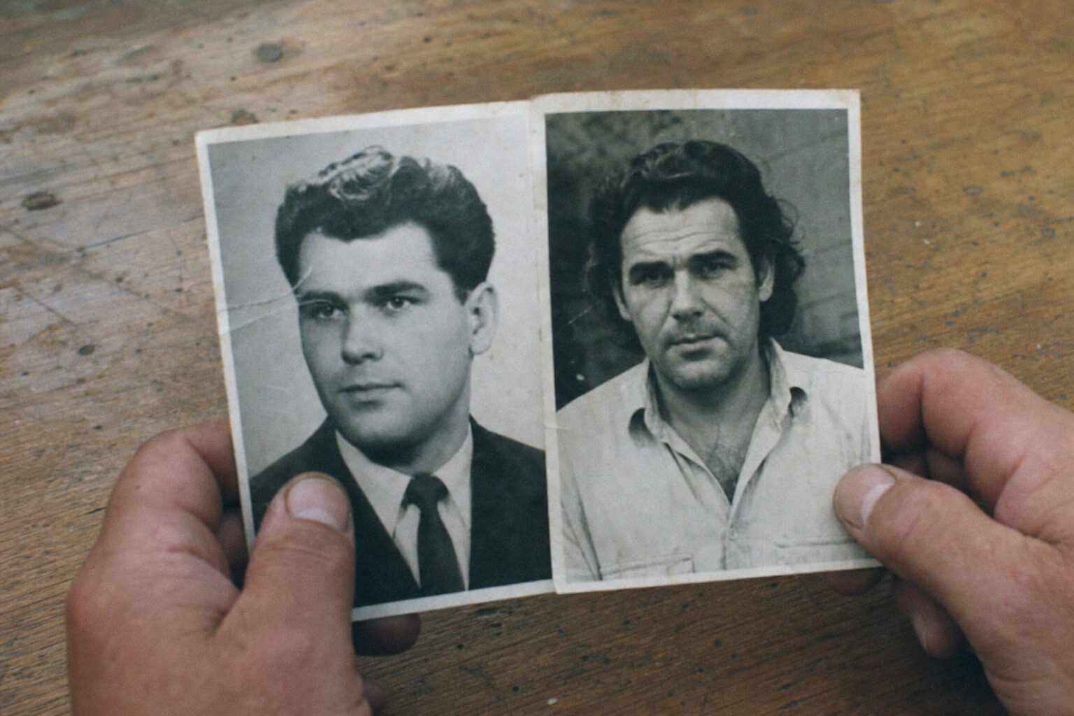 A man's hands comparing two black-and-white photographs