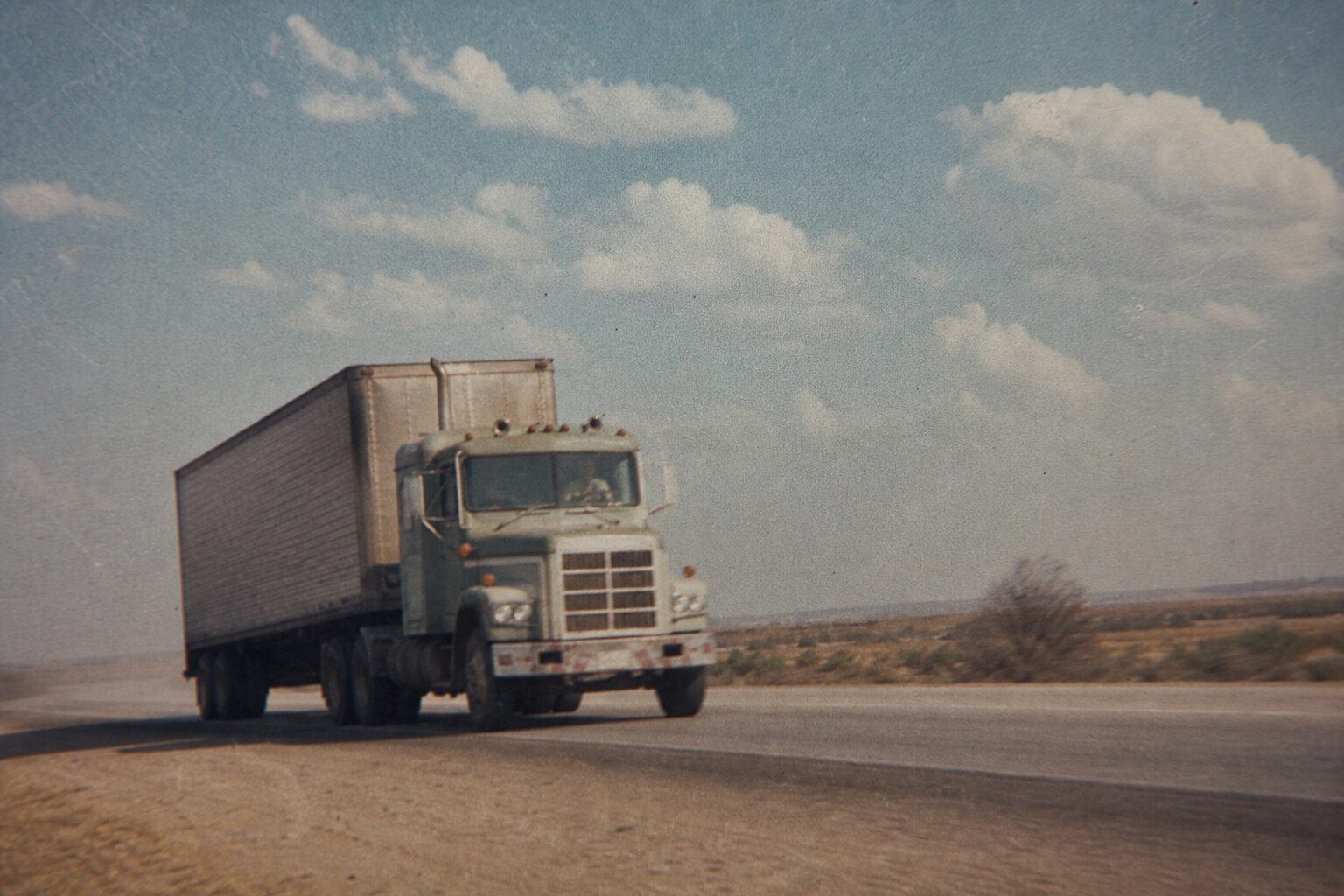 A long-haul truck driving a Texas highway (flashback)