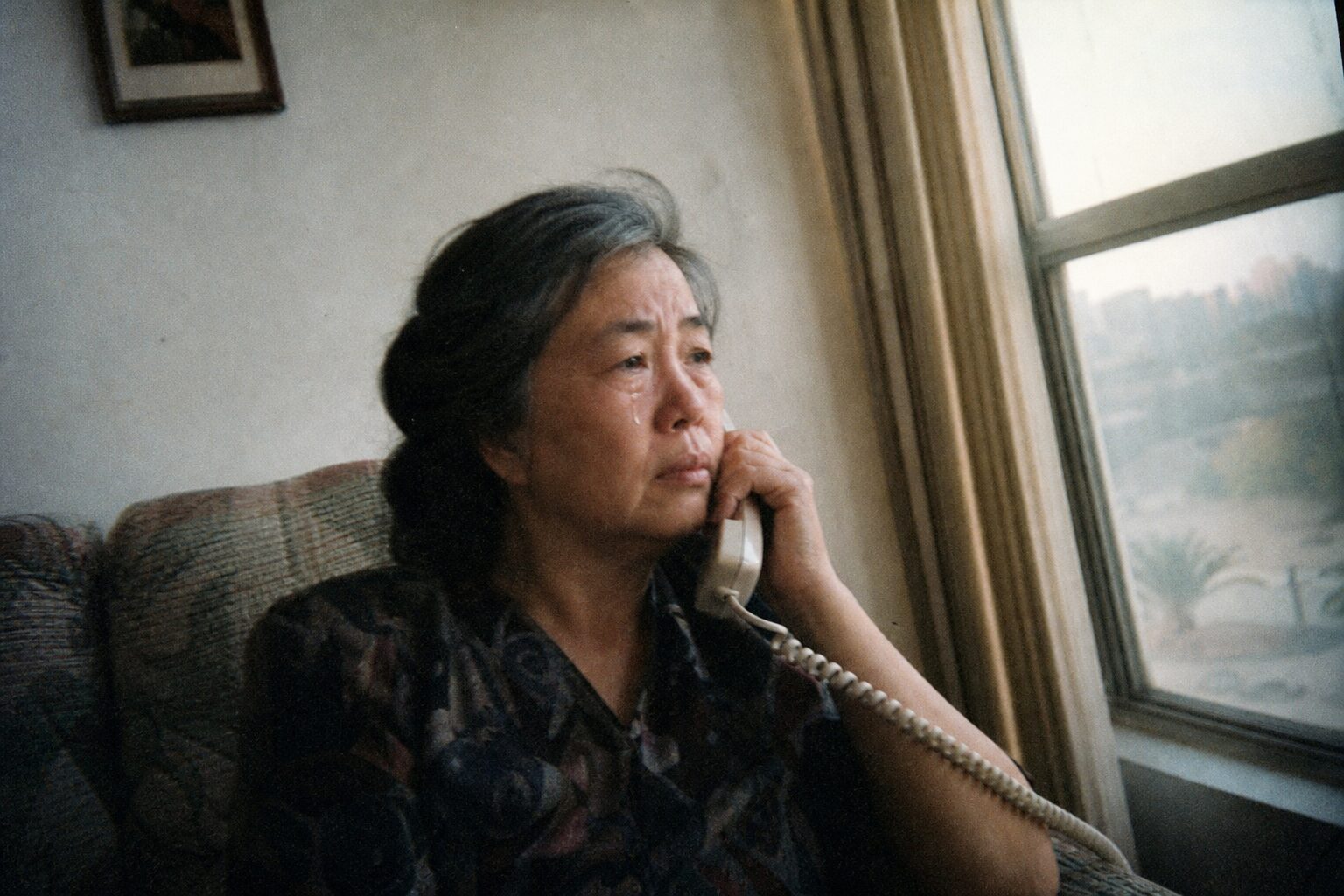 A middle-aged woman quietly crying on the phone