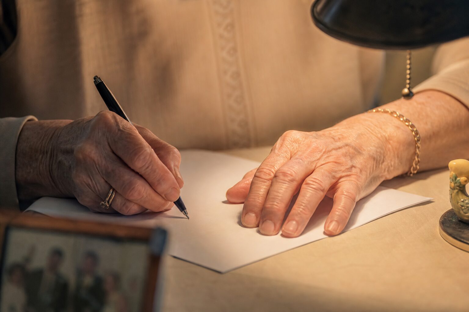 An elderly woman's hands writing a careful handwritten letter