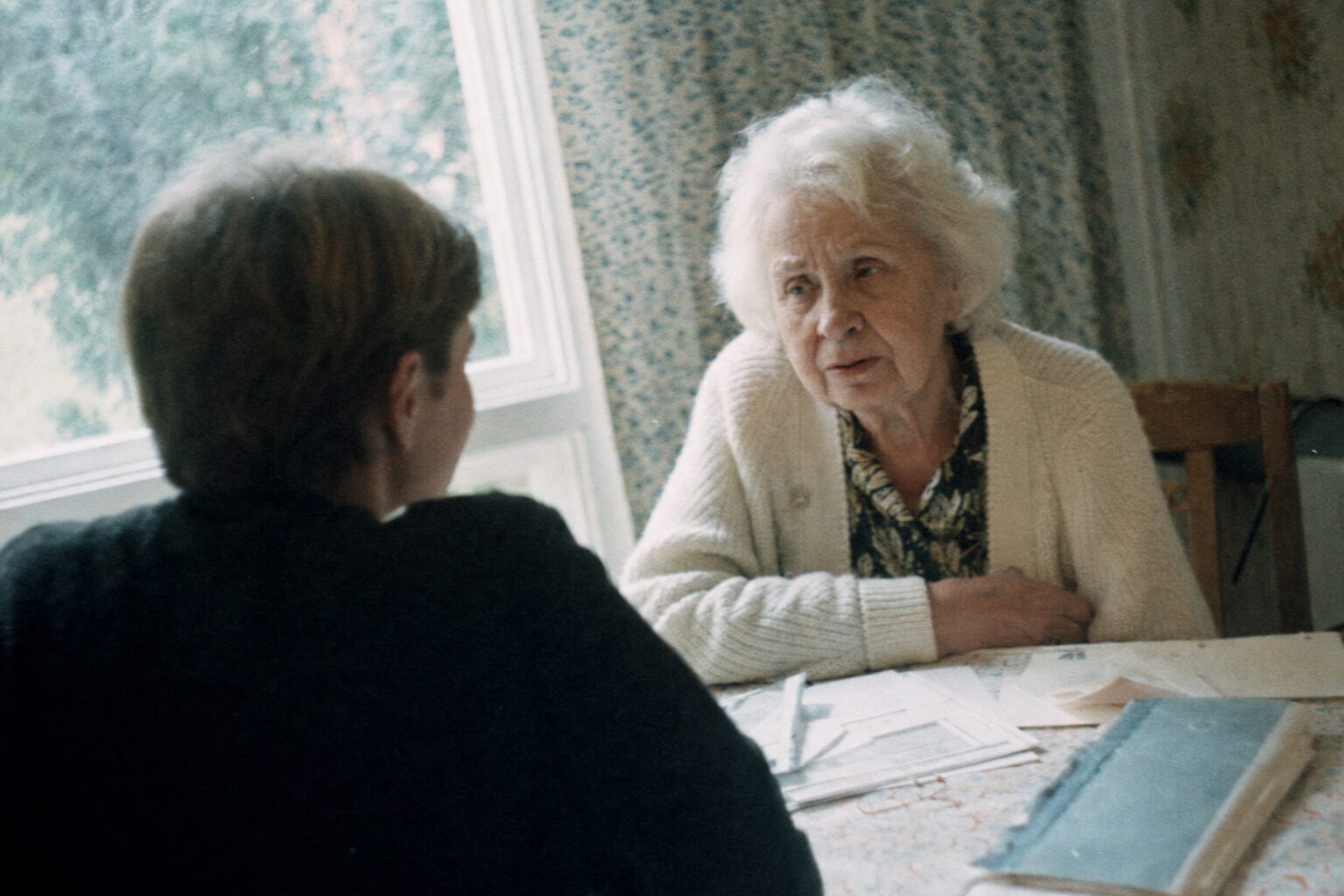 An elderly woman speaking quietly to her grandson in profile