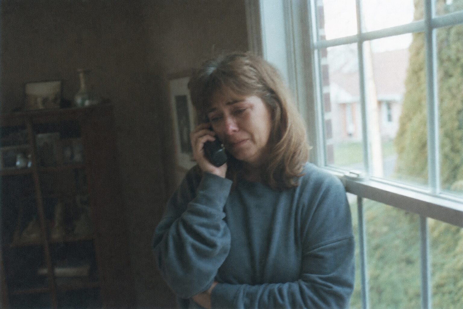 A middle-aged woman staring out the window while holding a phone