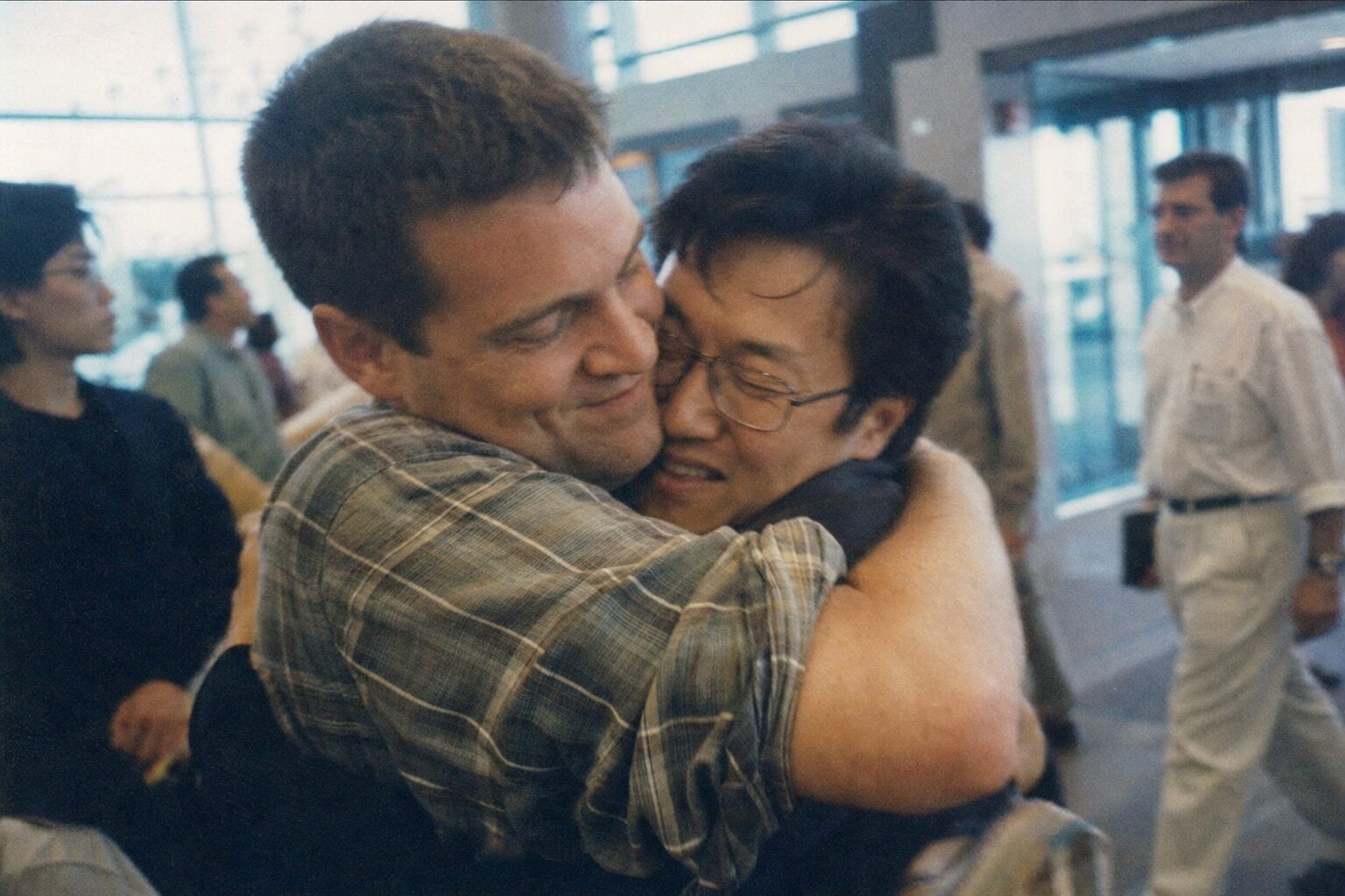 Two men embracing for the first time at an airport