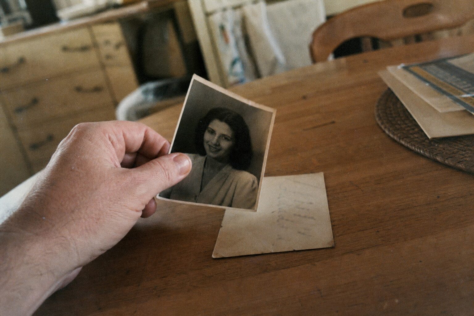 A woman's finger pointing at handwriting on the back of a photograph