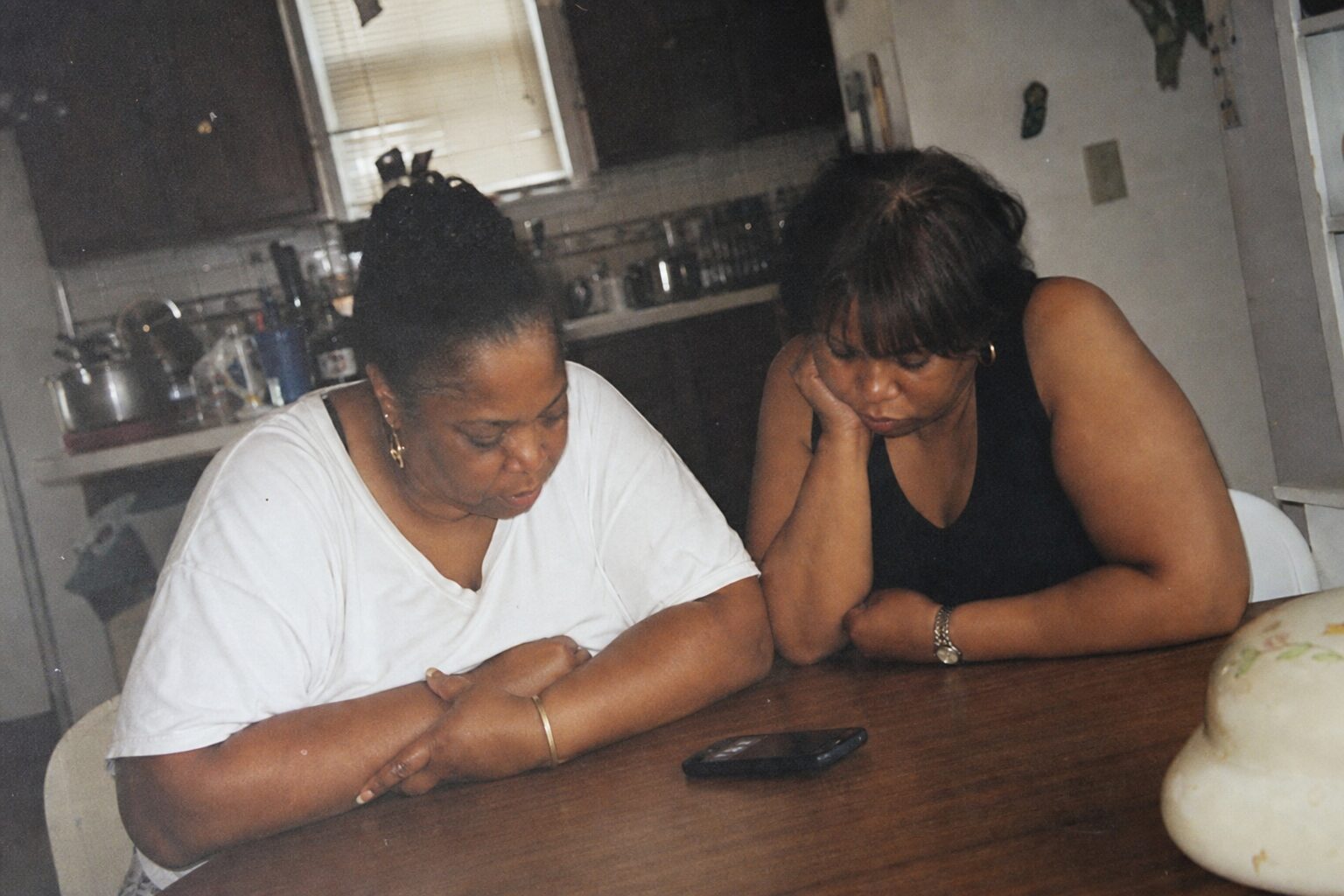Two sisters facing each other with a speakerphone between them