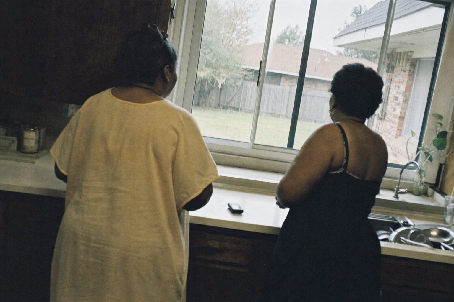Two sisters looking out a window after ending a phone call