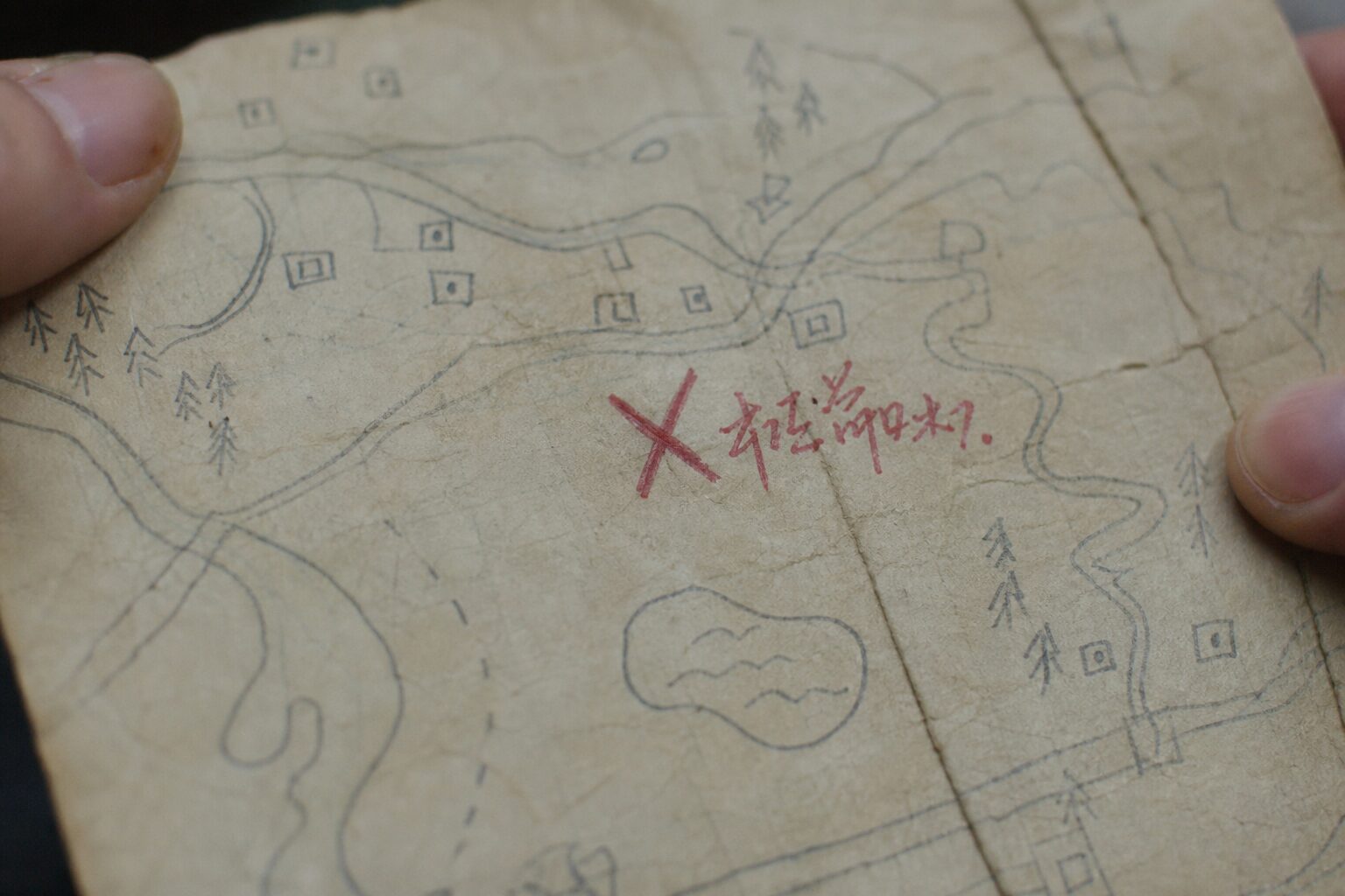 Close-up of a hand-drawn map with a large red X marked in red pen at one location